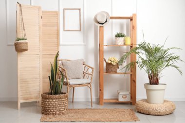 Oturma odasının iç kısmında hasır sandalye, askılık ve katlanır ekran.