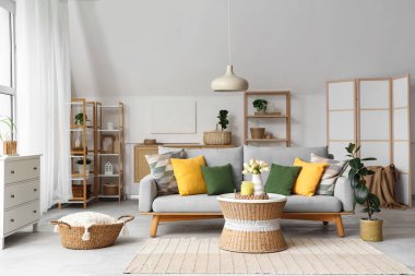 Koltuk, hasır sepet ve masa aydınlık ve rahat oturma odasının içinde.