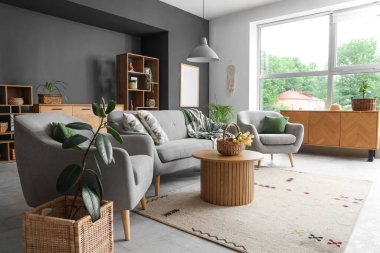 Koltuk, koltuk ve hasır sepet. Oturma odasındaki ahşap masada laleler.