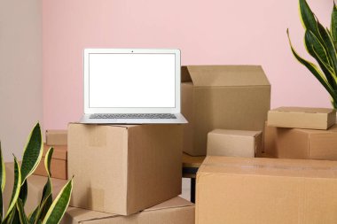 Pembe duvarın yanındaki kutuları taşıyan boş dizüstü bilgisayar.