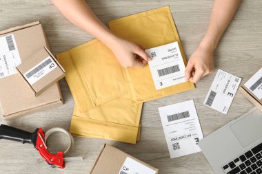Kadın postacı etiketi paket üzerine yapıştırıyor, üst görünüm