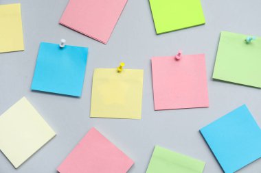 Gri arkaplana iğnelenmiş kağıt notlar