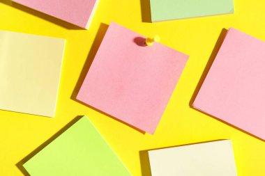 Sarı arkaplana iğnelenmiş pembe kağıt not