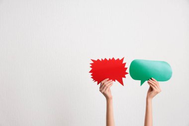 Beyaz arka planda farklı konuşma baloncukları olan kadın elleri