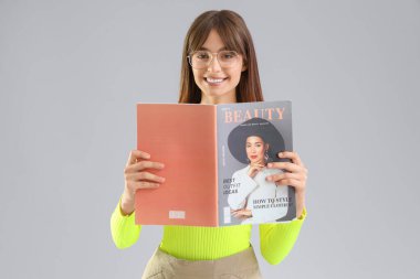 Açık arkaplanda dergi okuyan genç bir kadın