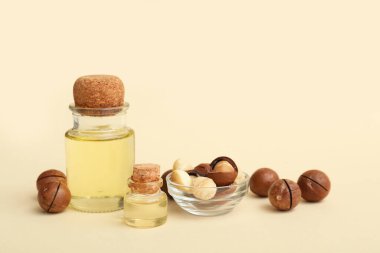 Bej arka planda macadamia yağı ve fındık şişeleri, yakın plan.