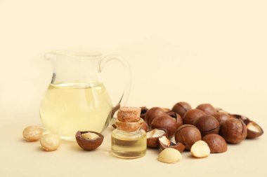 Bej arka planda macadamia yağı ve fındıklı şişe ve sürahi, yakın plan.