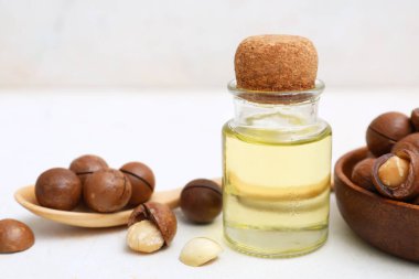 Hafif arka planda gerekli yağ ve macadamia fındıkları, yakın plan.