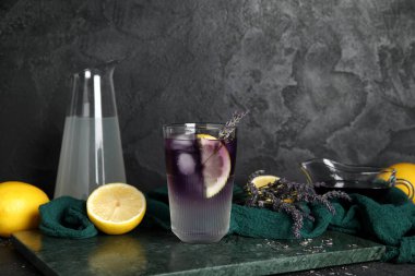 Koyu arkaplanda soğuk lavantalı limonata, çiçek, limon ve şurup karışımı.
