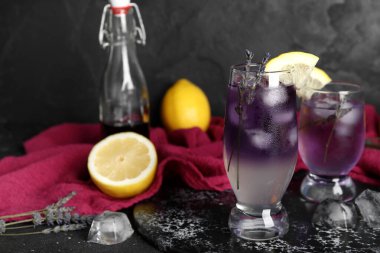 Koyu arkaplanda soğuk lavantalı limonata, limon ve şurup.