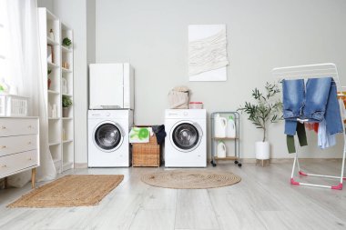 Çamaşır makinesi, kurutma makinesi ve çamaşır sepetinin olduğu banyonun içi.