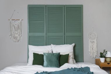 Yatak odasında yumuşak yeşil yastıkları olan rahat bir yatak.