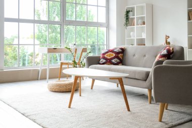 Gri kanepesi, koltuğu ve masaları olan oturma odasının içinde.