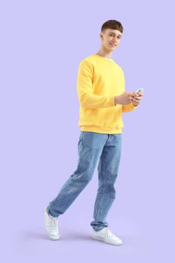 Genç adam eflatun arkaplanda cep telefonu kullanıyor.