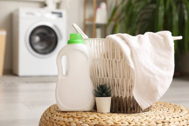 Havlulu sepet, ev bitkisi ve banyoda hasır puf üzerine çamaşır deterjanı.