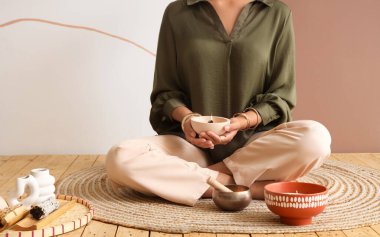Palo Santo 'lu genç kadın renk duvarının yanında oturuyor.