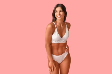 Güzel, genç, mutlu, pembe arka planda iç çamaşırlı, pozitif kadın.