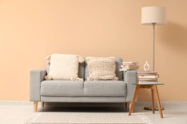 Gri kanepe, lamba ve kitap yığını bej duvarın yanındaki sehpada.