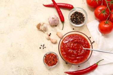 Bir kase kırmızı biber sosu ve beyaz arka planda farklı malzemeler.