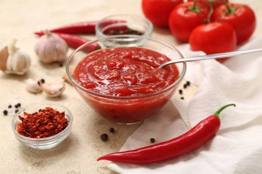 Bir kase kırmızı biber sosu ve beyaz arka planda farklı malzemeler.