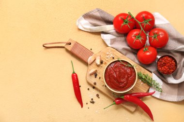 Bir kase acı biber sosu ve sarı arka planda farklı malzemeler.