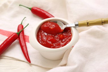 Bir kase kırmızı biber ve beyaz ahşap arka planda taze biber.