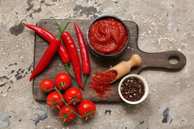 Bir kase acı biber sosu ve gri arka planda farklı malzemeler.