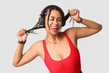 Gri arka planda rastalı kulaklıklı Afro-Amerikan bir kadın.