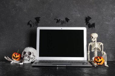 Karanlık arka planda Cadılar Bayramı kutlamaları için modern dizüstü bilgisayar ve dekor