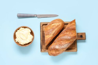 Arkaplanda taze ekmek ve tereyağı olan ahşap tahta.