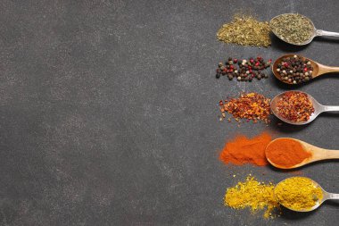 Koyu arka planda farklı aromatik baharatlara sahip kaşıklar.