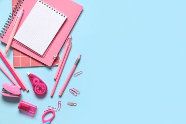 Mavi arkaplanda farklı kırtasiye malzemesi olan boş bir defter