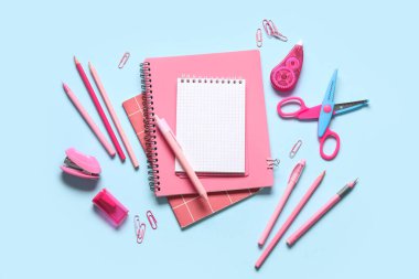 Mavi arkaplanda farklı kırtasiye malzemesi olan boş bir defter