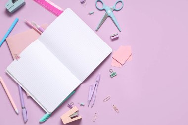 Leylak arka planında farklı kırtasiye malzemesi olan boş bir defter