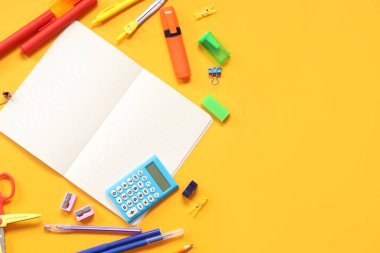 Turuncu arka planda farklı kırtasiye malzemesi içeren boş bir defter