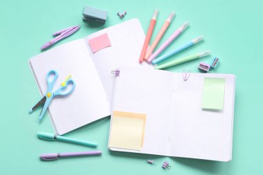 Mavi arkaplanda farklı kırtasiye malzemelerine sahip boş defterler