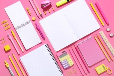 Pembe arka planda farklı kırtasiye malzemesi içeren boş defterler