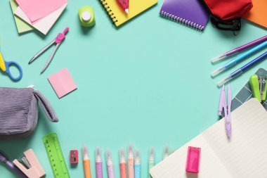 Turkuaz arka planda farklı kırtasiye malzemesi içeren not defterlerinden yapılmış çerçeve