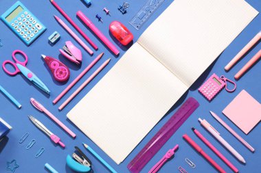 Mavi arkaplanda farklı kırtasiye malzemesi olan boş bir defter