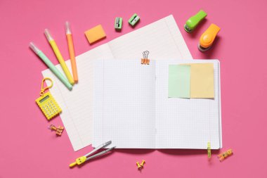 Pembe arka planda farklı kırtasiye malzemesi içeren boş defterler