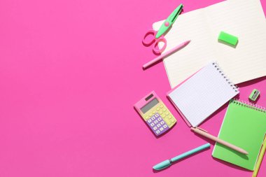 Pembe arka planda farklı kırtasiye malzemesi içeren boş defterler