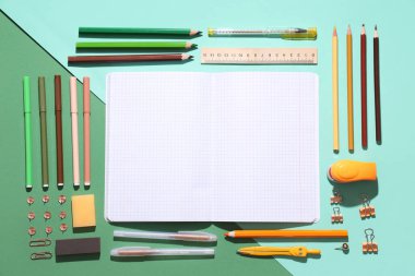 Renkli arkaplanda farklı kırtasiye malzemelerine sahip boş defter
