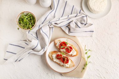 Lezzetli domates bruschetta ile ricotta ve beyaz arka planda bir kase mikro yeşil.