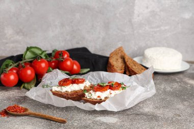 Gri arka planda ricotta soslu lezzetli domates bruschetta kağıdı.