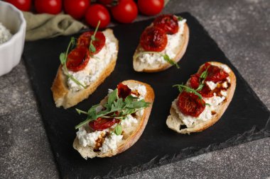 Gri arka planda ricotta soslu lezzetli domates bruschetta.