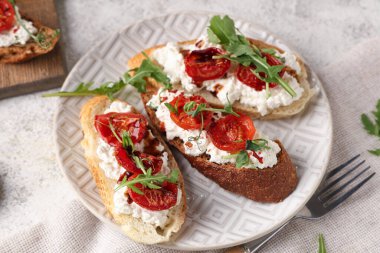 Beyaz arka planda ricotta ve roka ile lezzetli domates bruschetta tabağı.