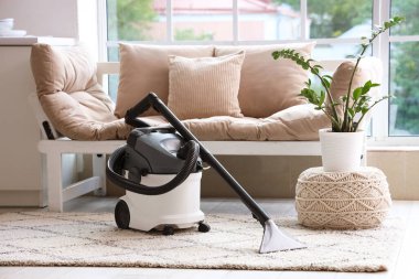 Evdeki beyaz kanepenin yanındaki halının üzerinde modern elektrikli süpürge.