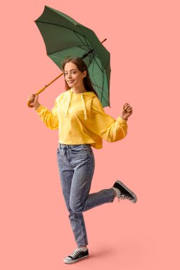 Pembe arka planda yeşil şemsiyeli güzel bir kadın.