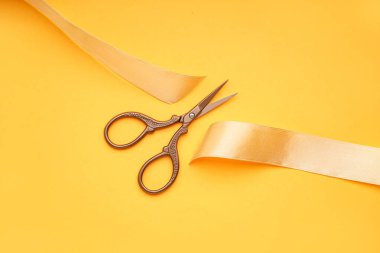 Sarı arkaplanda saten kurdele ve makas kes