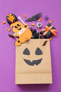 Renkli arkaplanda Cadılar Bayramı için alışveriş torbası, hediye, süs ve tatlı kompozisyonu